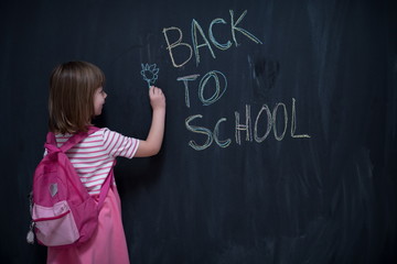 school girl child with backpack writing  chalkboard