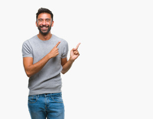 Adult hispanic man over isolated background smiling and looking at the camera pointing with two hands and fingers to the side.