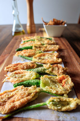 Fried zucchini squash courgette flowers on a wooden table. Italian appetiser.