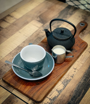 Cast Iron Tea pot with grey cup and saucer. Milk.