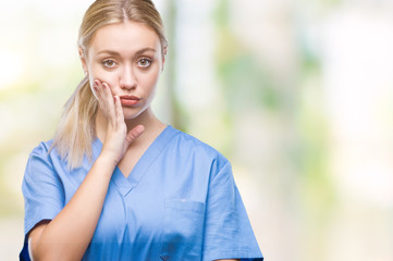 Young blonde surgeon doctor woman wearing medical uniform over isolated background thinking looking tired and bored with depression problems with crossed arms.