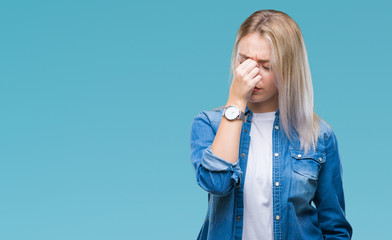 Young blonde woman over isolated background tired rubbing nose and eyes feeling fatigue and headache. Stress and frustration concept.