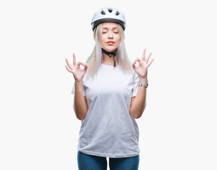 Young blonde woman wearing cyclist security helmet over isolated background relax and smiling with eyes closed doing meditation gesture with fingers. Yoga concept.