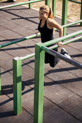 Fototapeta premium one young woman, 20-29 years, exercising outdoors in public park, outdoor gym, doing pull ups, push up, fitness equipment bars. elevated view.