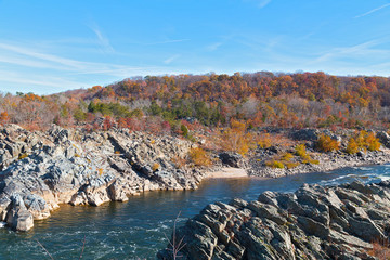 Riverbanks of treacherous Potomac River and autumn forest nearby. Great Falls State Park landscape with rocky terrain, forests and the river.