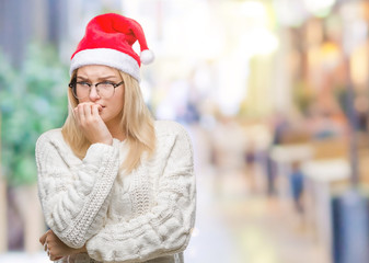 Young caucasian woman wearing christmas hat over isolated background looking stressed and nervous with hands on mouth biting nails. Anxiety problem.