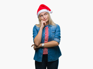 Young caucasian woman wearing christmas hat over isolated background with hand on chin thinking about question, pensive expression. Smiling with thoughtful face. Doubt concept.
