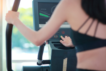 Naklejka premium portrait of young healthy and sporty woman using exercise machine in gym
