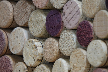 Genuine corks, from a mix of red and white wine bottles, are shown loosely stacked in a closeup, diagonal view with a shallow depth of field.