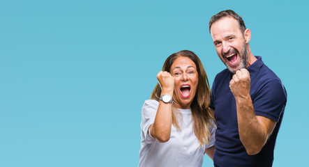 Middle age hispanic casual couple over isolated background very happy and excited doing winner gesture with arms raised, smiling and screaming for success. Celebration concept.