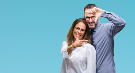 Middle age hispanic couple in love wearing glasses over isolated background smiling making frame with hands and fingers with happy face. Creativity and photography concept.