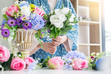 young women business owner florist making or Arranging Artificial flowers vest in her shop, craft and hand made concept