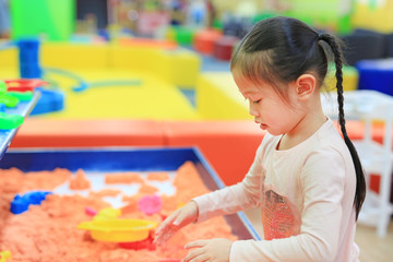 Asian kid girl playing kinetic sand.