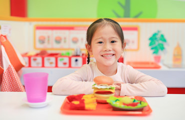 Portrait of little Asian kid girl playing in fast food shop.