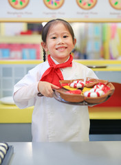Kid girl in a suit of the little chef make pizza, Cooking child concept.