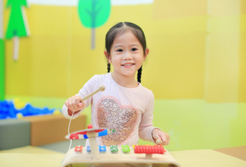 Asian kid girl having fun with Toys, musical instruments.