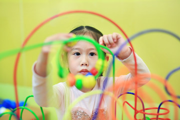 Close-up Asian child girl playing educational toy for brain development at kids room.