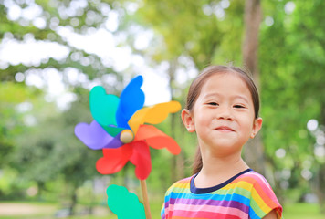 Close up cute little Asian child girl with wind turbine in the garden