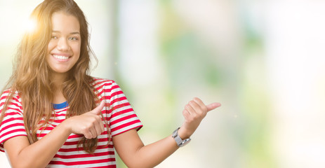 Young beautiful brunette woman wearing stripes t-shirt over isolated background Pointing to the back behind with hand and thumbs up, smiling confident
