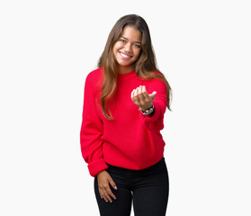 Young beautiful brunette woman wearing red winter sweater over isolated background Beckoning come here gesture with hand inviting happy and smiling