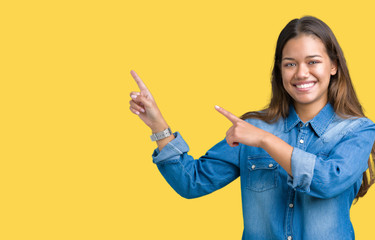 Young beautiful brunette woman wearing blue denim shirt over isolated background smiling and looking at the camera pointing with two hands and fingers to the side.