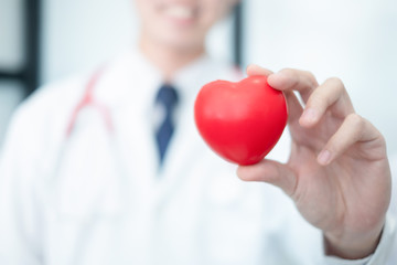 medical doctor in white uniform holding red heart shape, medical concept