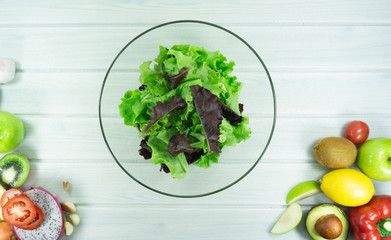 Healthy salad plate with green apple, tomatoes, avocado, Red chilli, Green pepper , lemon, Dragon fruit on white wooden background. Top view. Food and health. Clean eating..