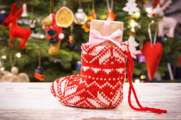 Wrapped gift for Christmas in red sock and christmas tree with decoration, festive time