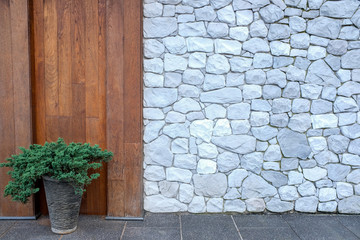 White rock wall background and wooden panelling wall with green plant in ceramic potted in an asian garden