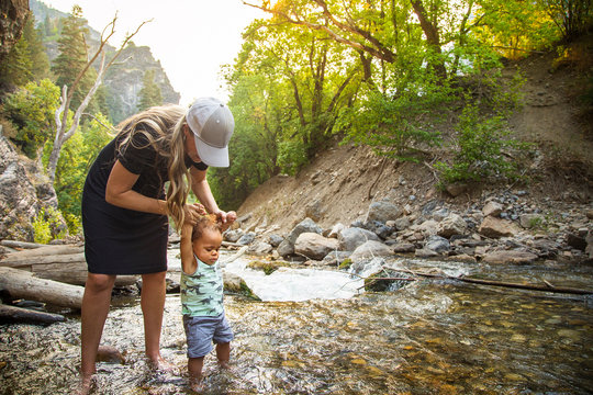 Woman and child hiking across a beautiful scenic mountain river. Walking in the mountain stream on a warm summer day together. lifestyle photo of a mother and her son in the outdoors