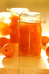 apricot jam  in glass jars and fresh ripe apricots on a yellow wooden board background in sun rays.Homemade jam