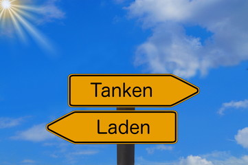 Zwei Schilder weisen auf eine Tankstelle und Ladestation für Elektro Autos