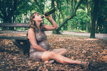 Pregnant woman drinking wine in the park - alcoholism concept