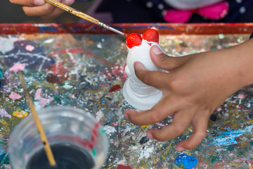 Obraz premium A child paints the colors of white plaster doll toys