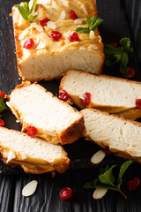 Freshly baked condensed milk loaf of bread decorated with dried cherries, almonds and mint close-up on the table. vertical