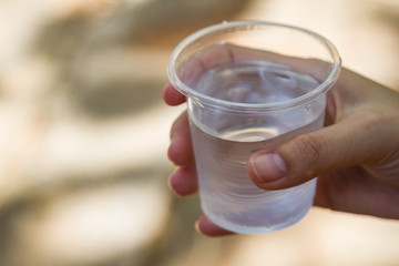 Female hand holding water glass with red liquid drink and water