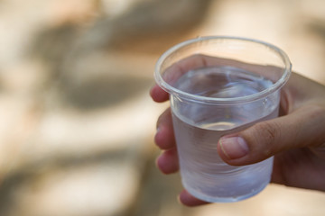 Female hand holding water glass with red liquid drink and water