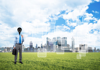 Camera headed man standing on green grass against modern cityscape