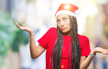 Young braided hair african american girl wearing christmas hat over isolated background clueless...