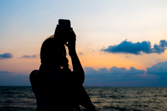 Silhouette picture of woman taking selfie during sunset