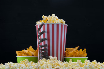 cinema snack, popcorn and two buckets of nachos on a black background
