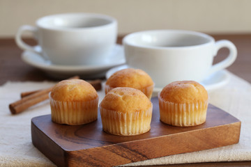 木のテーブルにのせた カップケーキ ホット コーヒー カップ