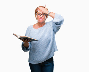 Senior caucasian woman reading a book over isolated background stressed with hand on head, shocked...