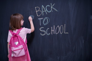 school girl child with backpack writing  chalkboard