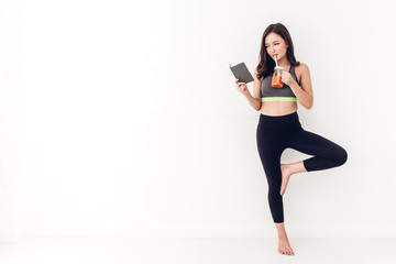 Sport woman in sportswear relax reading a book and drink fresh juice after workout against copy space for adding text with white wall background.Diet concept.Fitness and healthy lifestyle