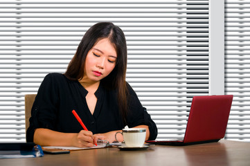 company corporate portrait of young beautiful and busy Asian Chinese woman working busy at modern office computer desk by venetian blinds window in business lifestyle