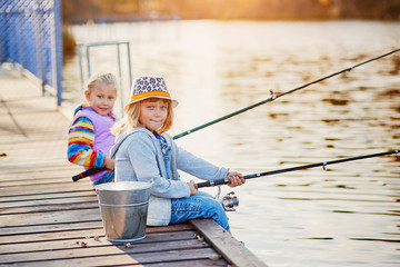 Two little girls fishing on the lake on a sunny morning.