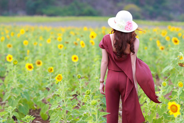 Portrait of beautiful woman having a happy time and enjoying among sunflower field in nature