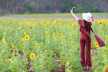 beautiful woman using smart phone while on holiday vacation among flowers field in nature