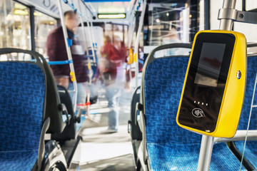 modern and comfortable City vehicle bus salon with empty passenger seats. Focus on yellow validator